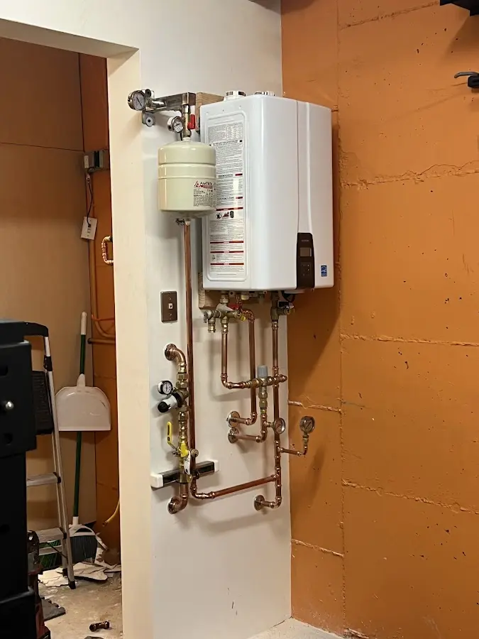 Plumbing technician inspecting water heater connections in Walpole
